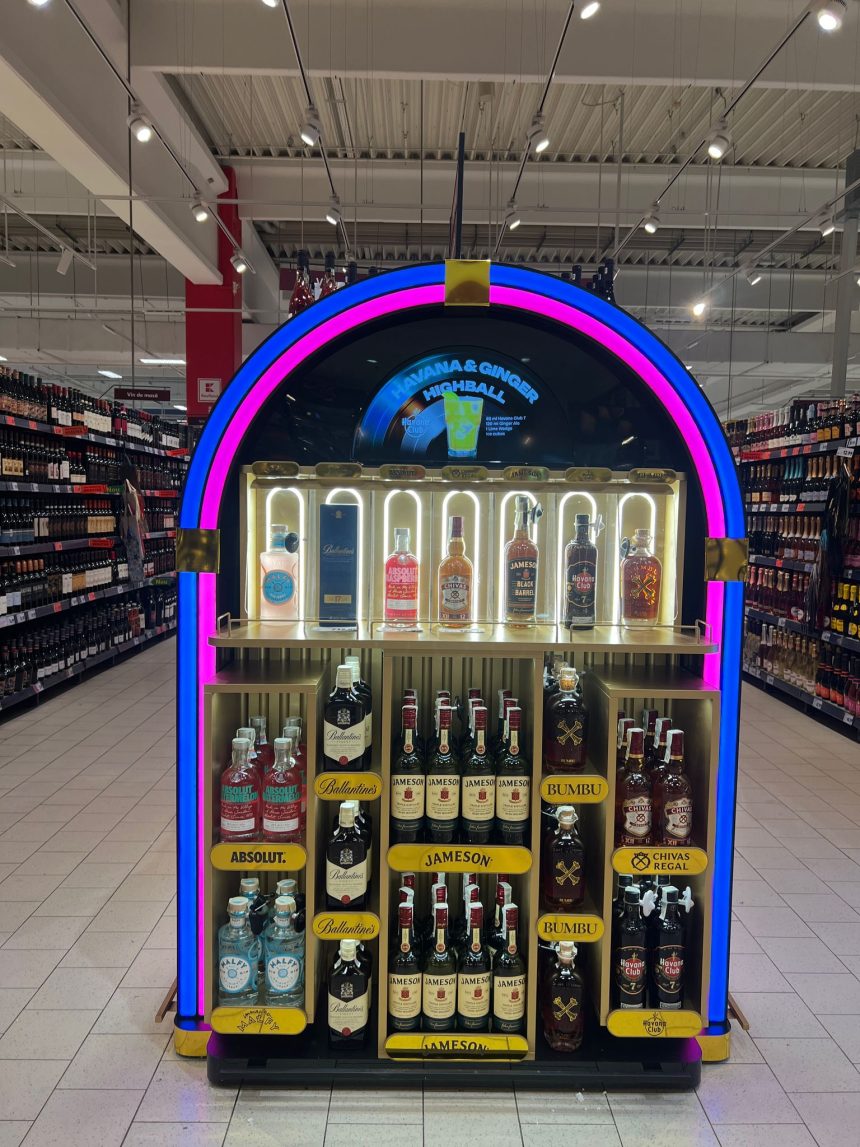 Display promoțional colorat cu whisky Jameson, rom Havana Club, Bumbu și vodcă Absolut într-un supermarket, evidențiind cocktailul Havana & Ginger.
